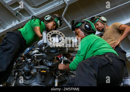 Les marins DE LA MER DES PHILIPPINES (15 mars 2022) effectuent l’entretien de l’assemblage de la broche et de la charnière d’un hélicoptère MH-60s Sea Hawk, affecté aux “Chargers” de l’Escadron de combat de la mer (HSC) 14, dans la baie hangar, à bord du porte-avions de la classe Nimitz USS Abraham Lincoln (CVN 72). Abraham Lincoln Strike Group est en cours de déploiement prévu dans la zone d'exploitation de la flotte américaine 7th afin d'améliorer l'interopérabilité par le biais d'alliances et de partenariats tout en servant de force de réaction prête à l'emploi pour soutenir une région libre et ouverte d'Indo-Pacifique. Banque D'Images