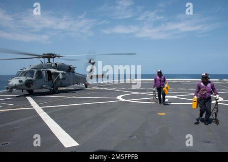220314-N-XB010-1005 MER DE CHINE ORIENTALE (14 mars 2022) avion Boatswain's Mate (Handling) 3rd classe Terrence Lofton, de Mobile, Ala, à gauche, Et Airman Tammaze Rubio, de Little Rock, en Arkansas, revient du retrait des cales et des chaînes d'un hélicoptère MH-60s Sea Hawk des « Archanges » de l'Escadron de combat de la mer (HSC) 25, détachement 6, sur le pont de vol de l'USS New Orleans (LPD 18). La Nouvelle-Orléans, qui fait partie de l'America Amphiobie Ready Group, ainsi que l'unité expéditionnaire maritime 31st, opère dans la zone US 7th Fleet, chargée d'améliorer l'interopérabilité Banque D'Images