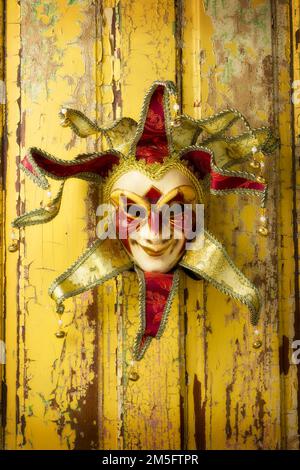 Madi gras Jester masque suspendu sur l'ancienne porte jaune usée encore la vie Banque D'Images