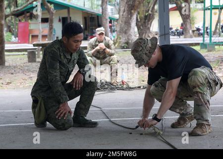 Alexander Saura, un fantassin affecté à l'équipe de combat de la brigade de 1st, observe comme un instructeur d'école de jungle examine son système de poulie z pendant le cours d'entraînement des opérations de la jungle tenu à Salaknib 2022 sur fort Magsaysay, Nueva Ecija, Philippines, 15 mars 2022. Le cours de formation Jungle Operations visait à préparer les soldats des États-Unis et des Philippines au terrain de la jungle qu’ils pourraient rencontrer autour de l’Indo-Pacifique, en s’appuyant sur la mission de Salaknib d’accroître la préparation et l’interopérabilité combinées. Banque D'Images