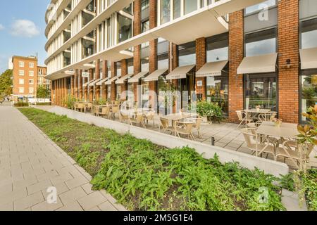 un espace extérieur avec des tables, des chaises et des parasols sur le trottoir devant un bâtiment qui est bricolé Banque D'Images