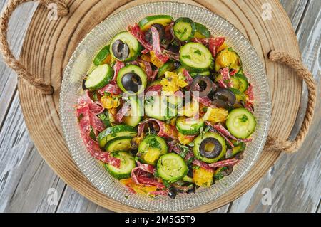 Salade avec courgettes, oranges et salami de cuisine gastronomique française, sur fond de bois. Pose à plat. Banque D'Images