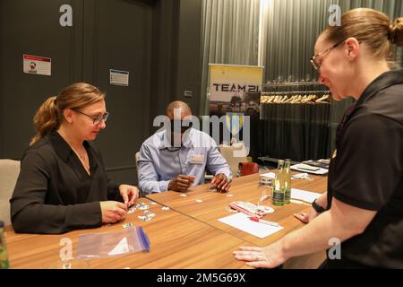 Les conseillers en égalité des chances Sgt. 1st classe Olga Kuzubov, 21st Theatre Sustment Command (l) et Sgt. 1st classe Krista McDowell, 18th brigade de la police militaire (r) assistent le Sgt. Maj. Eric Terrell, des États-Unis Armée Europe-Afrique Egalité des chances, dans un exercice de renforcement d'équipe lors du Symposium militaire sur l'égalité des chances 15-18 mars 2022 à Berlin. L'événement de formation a été parrainé par 21st TSC EQUAL Opportunity. Banque D'Images