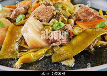Ragoût d'agneau avec légumes de saison sur une assiette noire. Gros plan. Banque D'Images
