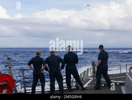 Des marins DE LA MER DES PHILIPPINES (16 mars 2022) à bord d'un destroyer-missile guidé de classe Arleigh Burke USS Higgins (DDG 76) regardent un hélicoptère récupérer une torpille pendant les opérations courantes en cours. Higgins est affecté au commandant de la Force opérationnelle (CTF) 71/Destroyer Squadron (DESRON) 15, le plus grand DESRON déployé à l’avant de la Marine et la principale force de surface de la flotte américaine 7th. Banque D'Images