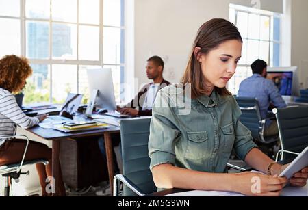Connecté au réseau sans fil Works. une jeune femme utilisant une tablette numérique à son bureau dans un bureau moderne. Banque D'Images