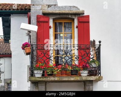 Fenêtre typique avec balcon, volets rouges et plantes en pot, détail de la façade, Espelette, département Pyrénées-Atlantiques. Région Banque D'Images