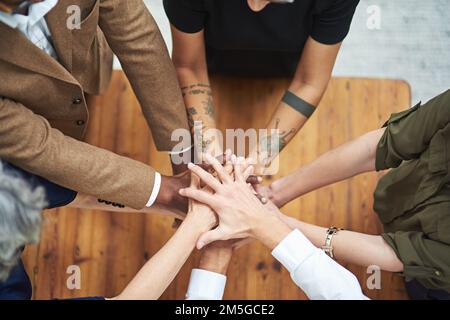 Tous ensemble maintenant. Photo en grand angle d'un groupe d'hommes d'affaires non identifiables mettant leurs mains dans un tas. Banque D'Images