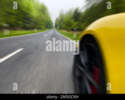 Photo avec caméra basse perspective de la vitesse de la voiture à grande vitesse sans limite de vitesse sur la route de campagne à travers la forêt, Allemagne Banque D'Images