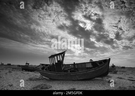 Brisés jetées de bateaux de pêche sur une plage de galets avec un paysage spectaculaire et nuageux, cimetière de bateaux, noir et blanc, Dungeness, Kent, Angleterre Banque D'Images