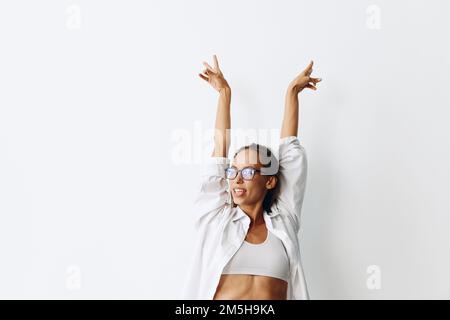 Portrait de femme avec peau bronzée portant des lunettes de vue sur un fond blanc souriant avec les dents et les mains en haut dans la joie Banque D'Images