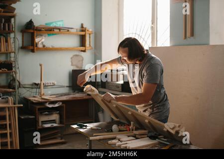 Un charpentier adulte, homme travaillant avec des outils dans sa boutique de bois - photo de stock Banque D'Images