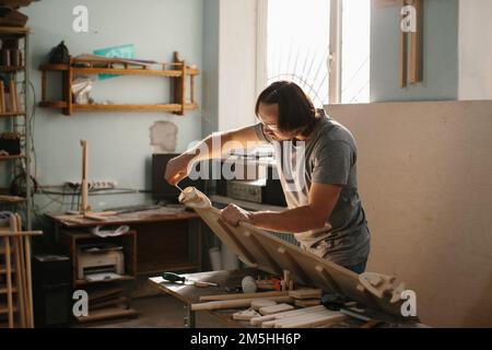 Un charpentier adulte, homme travaillant avec des outils dans sa boutique de bois - photo de stock Banque D'Images