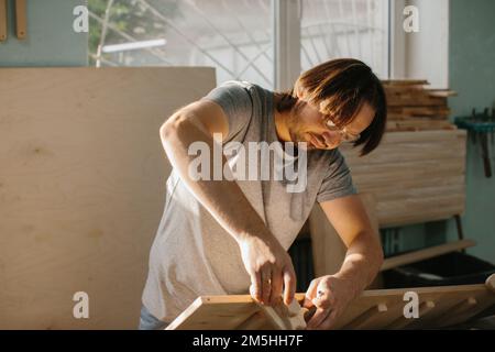 Un charpentier fait un ensemble d'escalade Montessori pour les enfants dans son atelier. Banque D'Images