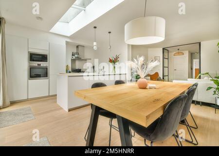 cuisine et salle à manger dans une maison avec parquet, murs blancs et lucarne au-dessus de la table Banque D'Images