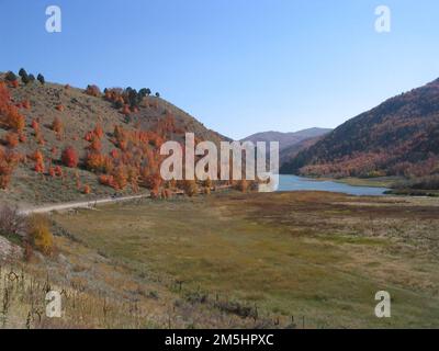 Pioneer Historic Byway - couleurs d'automne et réservoir Oneida Narrows. Niché entre les collines couvertes de majestueux couleurs d'automne à Oneida Narrows dans l'Idaho est un petit lac ou réservoir. Un camion conduit le long de la route de terre qui longe la montagne. Emplacement : Oneida Narrows, Idaho (42,277° N 111,750° O) Banque D'Images