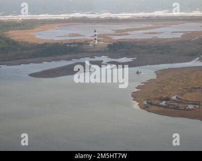 Outer Banks Scenic Byway - Station de lumière et centre d'accueil de l'île de Bodie dans le bord de mer national du Cap Hatteras. Une vue aérienne révèle la station de lumière de l'île Bodie de la route panoramique Outer Banks depuis l'est. Le phare est stoïque avec son « repère » à rayures noires et blanches horizontales, avec les quartiers blancs des Keepers et le Oil House à peine visibles à gauche. Les vagues de l'océan Atlantique créent une frange horizontale de mousse au loin. Lieu: Cape Hatteras National Seashore, Caroline du Nord (35,194° N 75,732° O) Banque D'Images