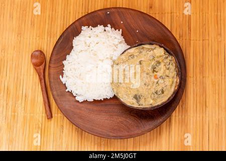 Ragoût de chou frisé traditionnel africain au lait de coco et à la farine d'arachide, servi dans une carapace de noix de coco au riz blanc : un plat délicieux et nutritif de Moza Banque D'Images