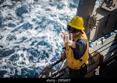 MER DES PHILIPPINES (18 mars 2022) classe du compagnon 3rd de Boatswain Daniel Bello-Jimenez, de San José (Californie), agit comme commandant de la plate-forme à bord du destroyer de missile guidé de la classe Arleigh Burke USS Dewey (DDG 105) lors d’un réapprovisionnement en mer avec le ravitailleur USNS John Ericsson (T-AO 194). Dewey est affecté au Destroyer Squadron (DESRON) 15 et est en train de soutenir une Indo-Pacifique libre et ouverte. CTF 71/DESRON 15 est la plus importante force de surface déployée par la Marine et la principale force de surface de la flotte américaine 7th. Banque D'Images