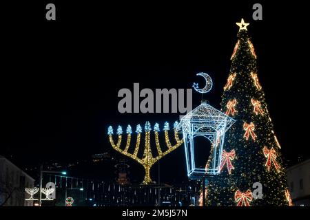 Un arbre de Noël décoré avec la menorah Hanukkah illuminée et le croissant de la nouvelle lune qui est associée à l'islam exposé dans le quartier de la colonie allemande à Haïfa, Israël comme la ville célèbre les vacances qui marque les vacances Hanukkah, Noël, et Ramadan vacances de trois religions principales: Christianisme, judaïsme et islam. Banque D'Images