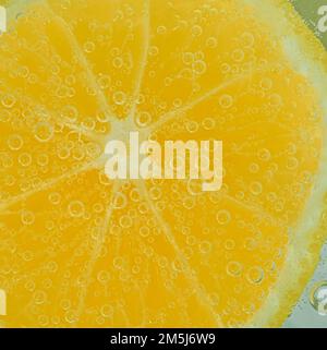 Tranche de citron frais dans du liquide avec des bulles. Gros plan d'une tranche de citron dans de l'eau sodée. Bulles sur citron. Tranche de citron dans de l'eau gazeuse. Banque D'Images