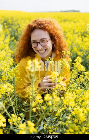 Femme caucasienne souriant dans le champ de fleurs jaunes Banque D'Images