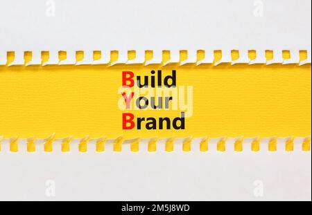 BYB construisez votre symbole de marque. Mots-clés BYB construisez votre marque sur un papier blanc sur un magnifique fond jaune. Business et BYB créent votre marque con Banque D'Images