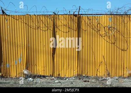 Paroi en métal ondulé jaune avec fil barbelé dans la zone industrielle du Bronx Banque D'Images