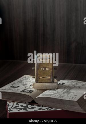 Vieux antique laiton Calendrier perpétuel de bureau montrant 1 janvier ( calendrier perpétuel d'époque ) placé sur et vieux livre avec fond en bois foncé. Nous Banque D'Images