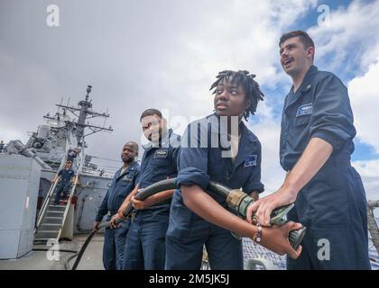 LES marins DE LA MER DES PHILIPPINES (19 mars 2022) apportent un tuyau à un tir simulé sur le pont de vol du destroyer-missile guidé de classe Arleigh Burke USS Higgins (DDG 76) pendant un exercice. Higgins est affecté au commandant de la Force opérationnelle (CTF) 71/Destroyer Squadron (DESRON) 15, le plus grand DESRON déployé à l’avant de la Marine et la principale force de surface de la flotte américaine 7th. Banque D'Images