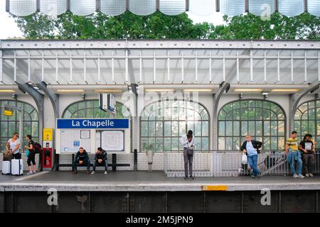 Paris, France - les gens attendent le prochain train à l'intérieur de la station de métro la Chapelle. Les navetteurs attendent sur la plate-forme. Intérieur en vitraux transparents. Banque D'Images