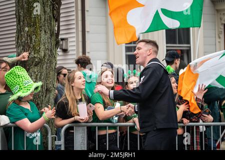 Joshua Hall, conseiller de la Marine, classe 1st, attaché au Navy Talent acquisition Group, Nouvelle-Angleterre, accueille les participants au défilé de la St Patrick de Boston, 2022. Cet événement a été le premier des marins à participer au défilé depuis 2019 en raison de préoccupations liées à la pandémie COVID-19. Banque D'Images