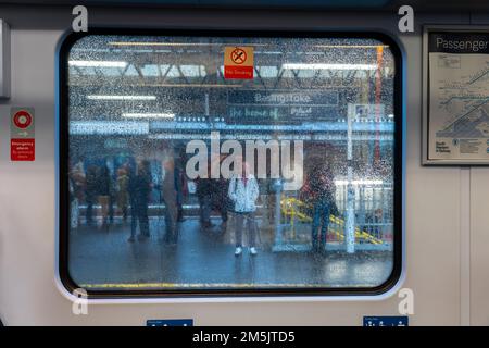 En regardant par la fenêtre de train couverte de raindrop à hors de focus les personnes se tenant sur une plate-forme de gare. Concept : services retardés. ROYAUME-UNI Banque D'Images