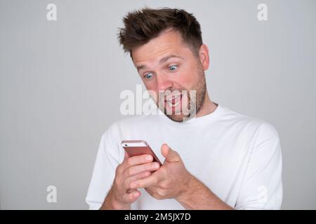homme regardant l'écran d'un smartphone, souriant en discutant avec un ami Banque D'Images