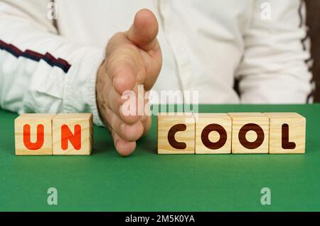 Un homme sépare les cubes avec l'inscription - UNCOOL ou COOL. Banque D'Images