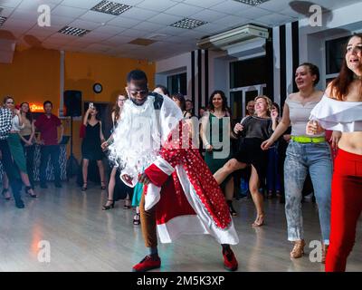 23-12-2022 Moscou, Russie. Professeur de danse afro-russe joue Ded Moroz (Père Noël. Grandfather Frost) et danse aussi avec le groupe - ils regardent Banque D'Images