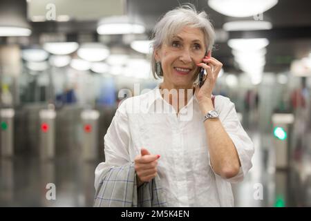 Femme caucasienne ayant une conversation téléphonique dans la station de métro Banque D'Images