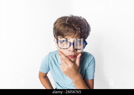 Un portrait de gros plan exagéré d'un petit garçon drôle avec des lunettes faisant un visage de pensée Banque D'Images