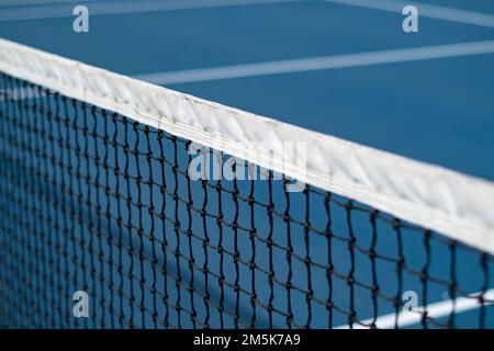 Un gros plan du filet de tennis diagonal avec des lignes blanches sur un court bleu, concept d'un match de tennis Banque D'Images