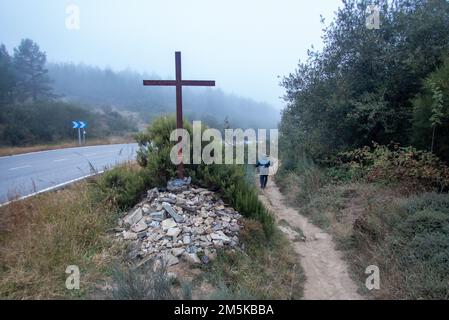 Un pèlerin dans la brume sur la voie Saint-Jacques en route sur la chaîne de montagnes entre Foncebadón et Ponferrada. Banque D'Images