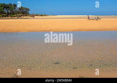 Homme tirant un kayak sur Moonee Beach au nord de Coffs Harbour Banque D'Images