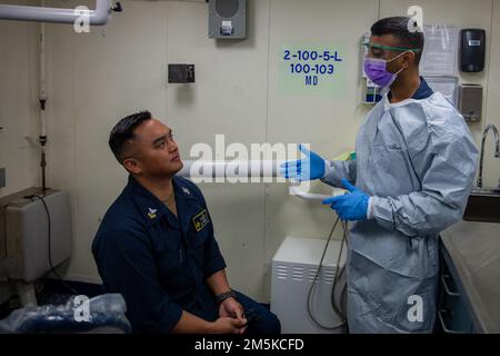 Hôpital Corpsman 1st classe Sujit Rajendran, à droite, de Mumbai, Inde, consulte l'hôpital Corpsman 1st classe Tristan Ricamona, de Las Vegas, à gauche, tous deux affectés au service dentaire de l'USS Gerald R. Ford (CVN 78), dans le principal service médical du navire, 22 mars 2022. Ford est en cours dans l'océan Atlantique en menant une certification de plate-forme de vol et des qualifications de transporteur d'ailes aériennes dans le cadre de la phase de base sur mesure du navire avant le déploiement opérationnel. Banque D'Images