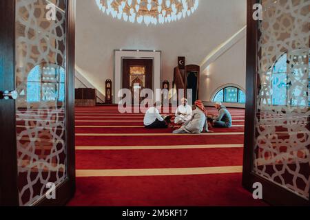 Un groupe de musulmans lisant le livre Saint du Coran dans une mosquée moderne pendant la fête musulmane du Ramadan Banque D'Images