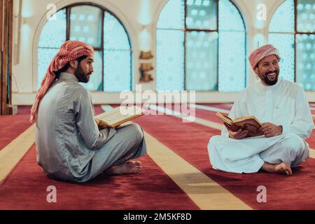 Un groupe de musulmans lisant le livre Saint du Coran dans une mosquée moderne pendant la fête musulmane du Ramadan Banque D'Images
