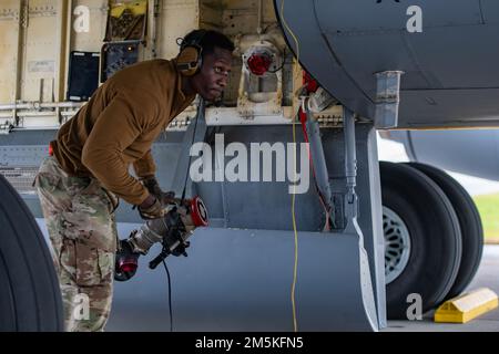 ÉTATS-UNIS Le sergent d'état-major de la Force aérienne Eddy Odongpinyokene, chef de l'équipage de conduite de l'unité de maintenance de 909th aéronefs, porte un tuyau de carburant sous un escadron de ravitaillement aérien KC-135 909th Stratotanker lors du premier ravitaillement en fosse chaude KC-135 dans le Pacifique, à la base aérienne de Kadena, au Japon (22 mars 2022). Les membres de l'escadron de préparation logistique 18th utilisent un camion de ravitaillement R-11, tandis que 909th membres de l'UMA font le plein en toute sécurité d'aéronefs. Banque D'Images