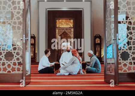 Un groupe de musulmans lisant le livre Saint du Coran dans une mosquée moderne pendant la fête musulmane du Ramadan Banque D'Images