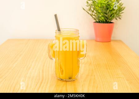Un smoothie à l'ananas mûr dans un bol en verre sur une table en pin Banque D'Images