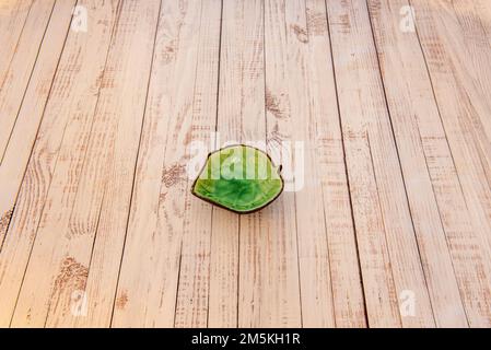 Un joli plat à trempette vert feuilles au centre d'une table en bois Banque D'Images