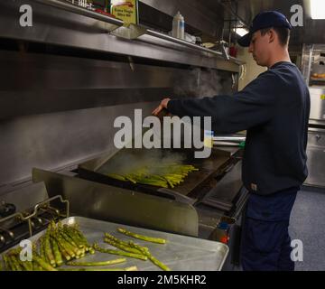 ÉTATS-UNIS Garde côtière maître de classe 2nd Christian Rocha, un spécialiste culinaire à bord du Cutter Spar de la Garde côtière, prépare le repas du soir en cours dans le fleuve Saint-Laurent, au 22 mars 2022. Spar et son équipage se rendent à Duluth, au Minnesota, après une période d'entretien d'un an à Baltimore. Banque D'Images