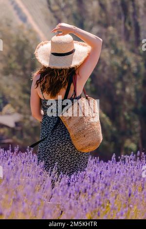 Femme dans un chapeau de paille marchant dans le champ de lavande, mode de vie de campagne Banque D'Images